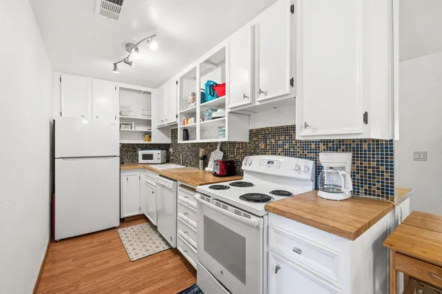 a kitchen with refrigerator a stove a sink dishwasher and white cabinets with wooden floor