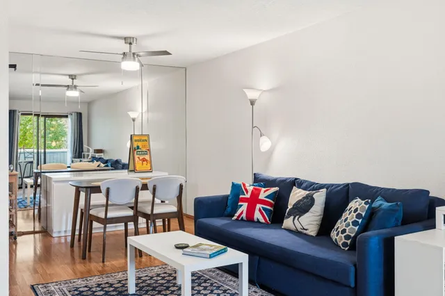 a living room with a couch and a dining table with wooden floor