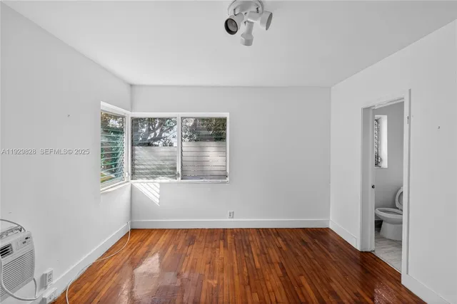 a view of an empty room with a window and wooden floor