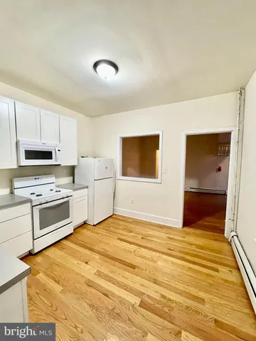 a kitchen with kitchen island a stove a refrigerator sink cabinets and wooden floor