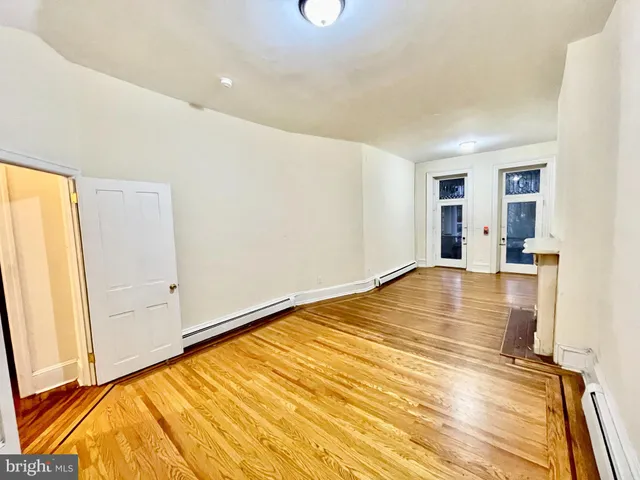 a view of an empty room with wooden floor and a fireplace