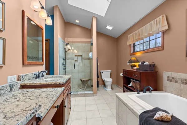 a bathroom with a granite countertop sink a mirror and a bathtub