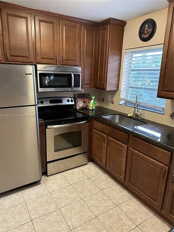 a kitchen with granite countertop wooden cabinets stainless steel appliances and a sink