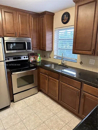 a kitchen with granite countertop a stove top oven sink and cabinets