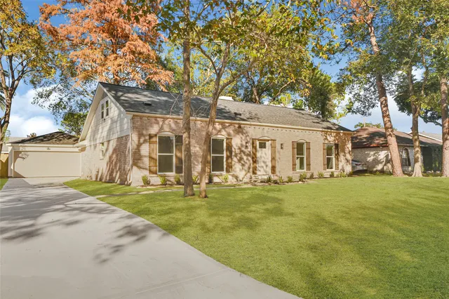 a view of a house with a big yard and large trees