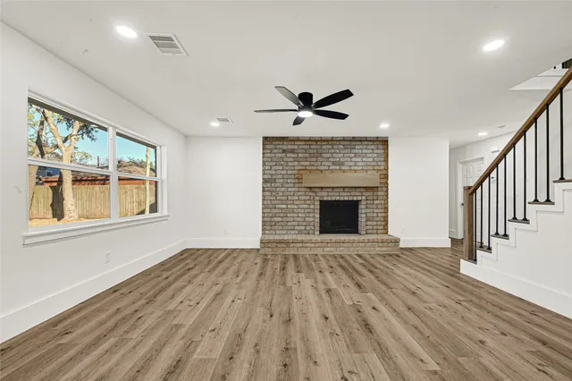 a view of an empty room with wooden floor and a fireplace