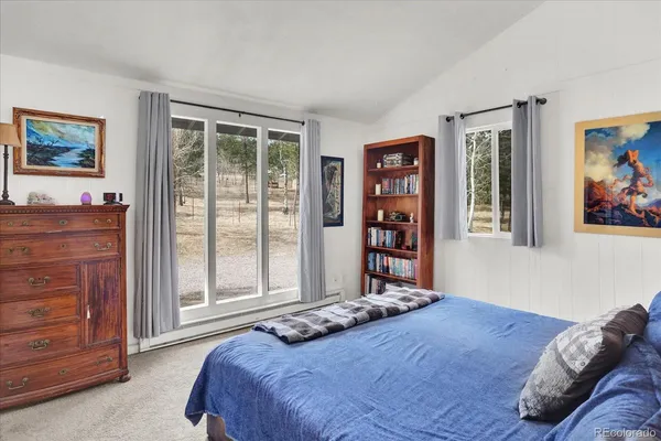 a bedroom with a bed painting on wall and a large window