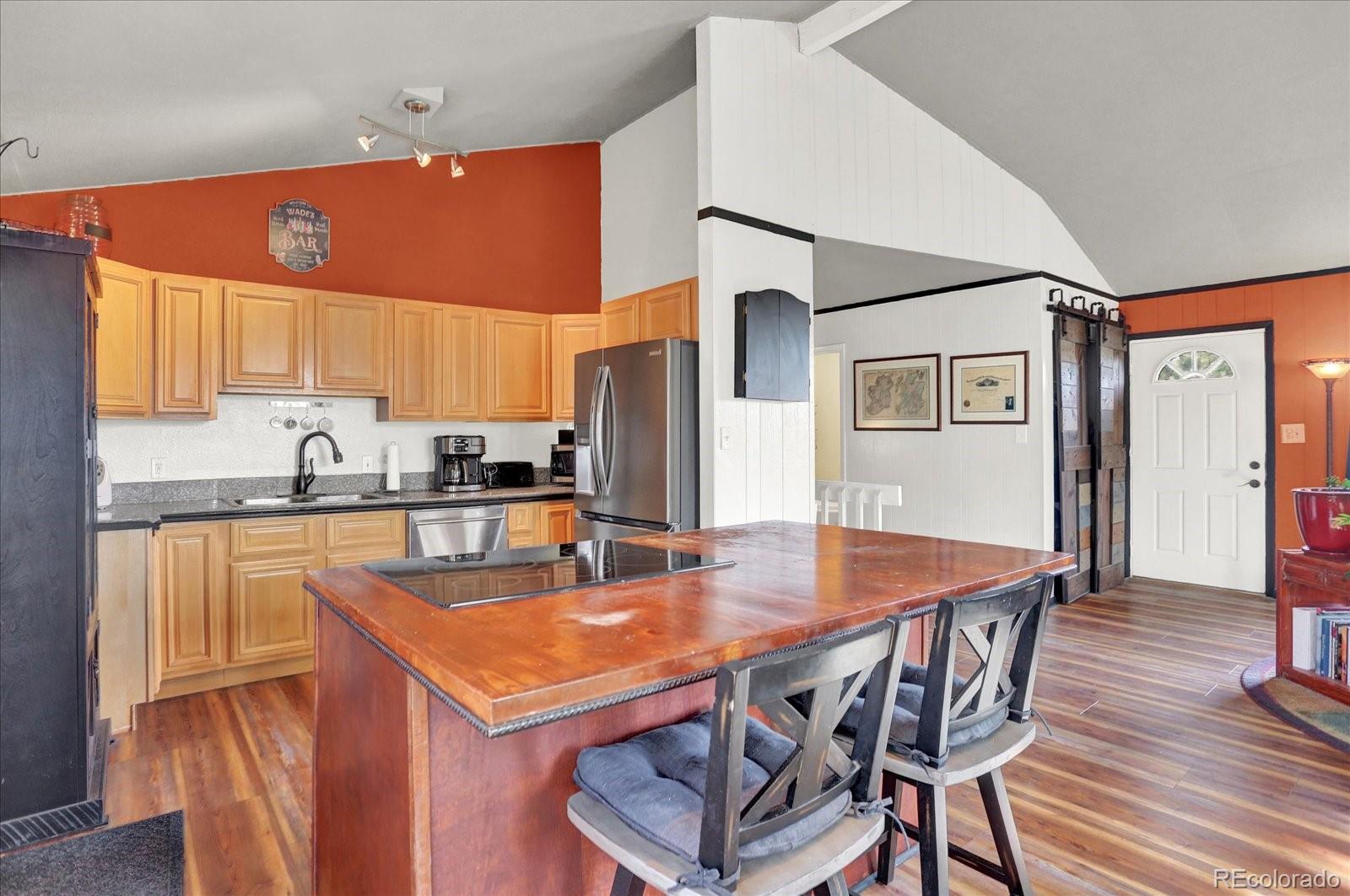 249 Burland Drive Bailey, CO 80421 - Photo 6 of 34 a kitchen with stainless steel appliances granite countertop a kitchen island a stove a refrigerator a sink a dining table and chairs with wooden floor