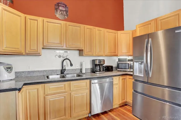 a kitchen with stainless steel appliances granite countertop a refrigerator sink and white cabinets