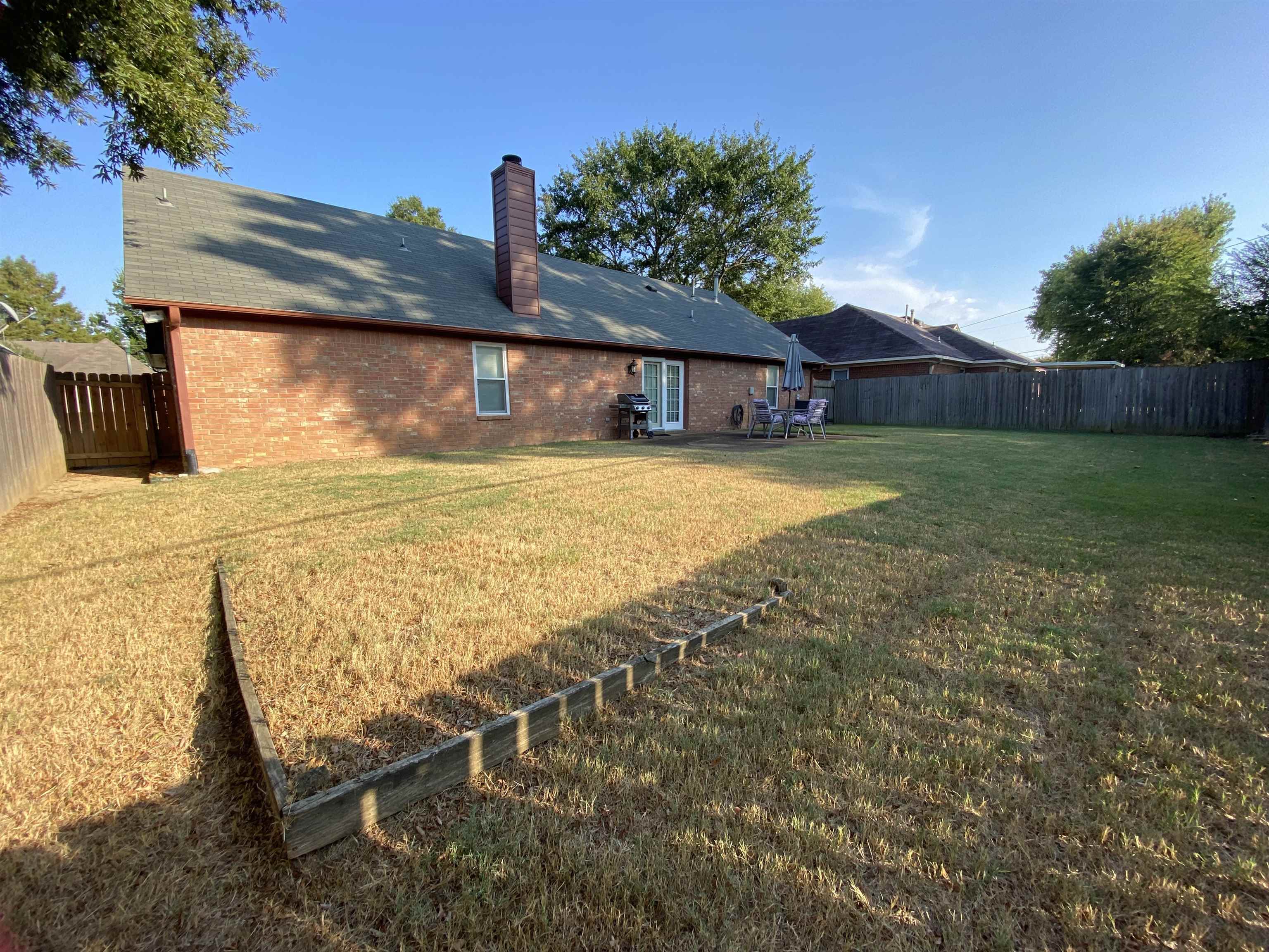 1235 Creeks Edge Cove Memphis, TN 38016 - Photo 15 of 15 Rear view of property featuring a fenced backyard, brick siding, a chimney, a patio, and roof with shingles