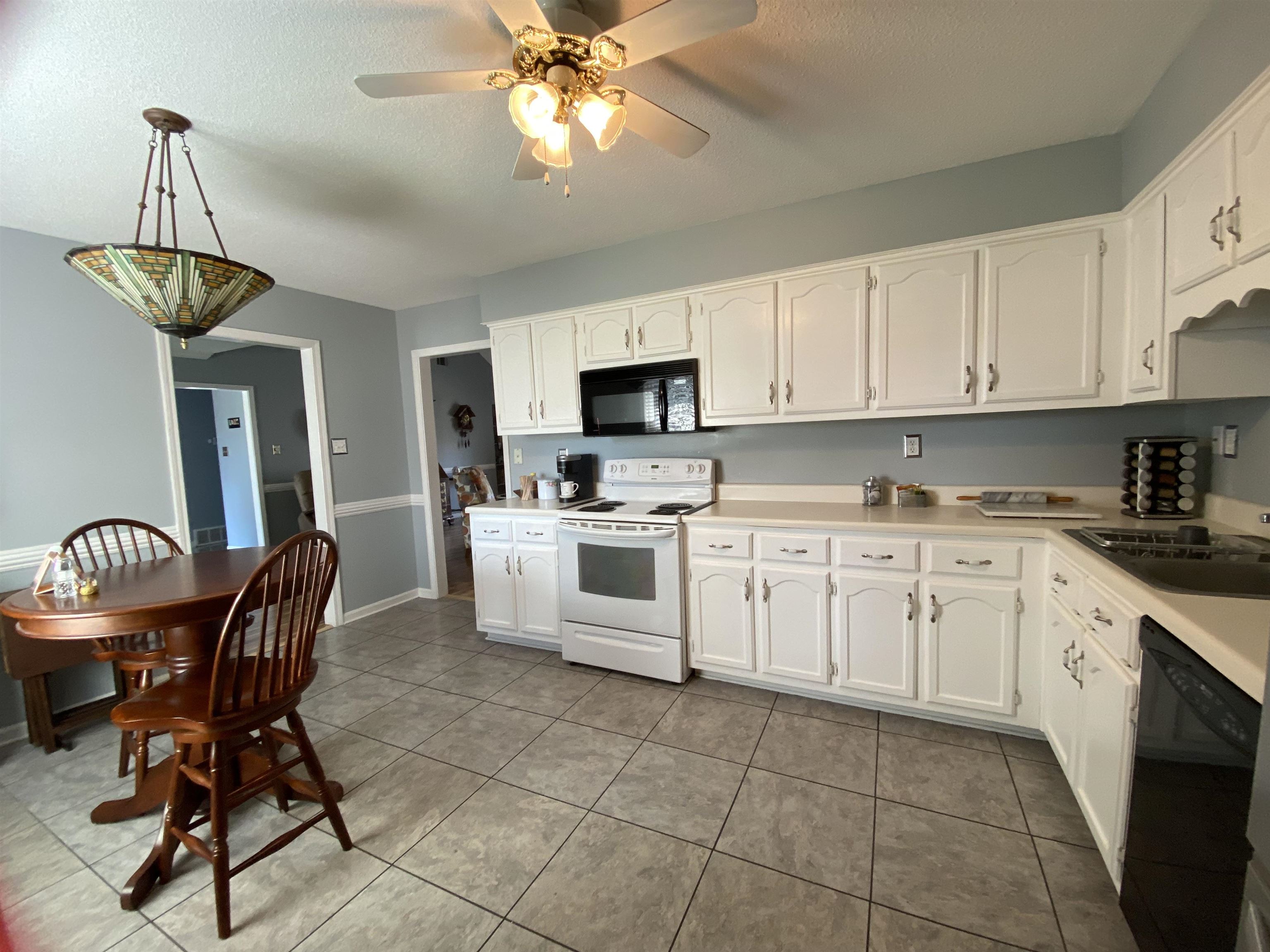 1235 Creeks Edge Cove Memphis, TN 38016 - Photo 8 of 15 Kitchen with black appliances, light countertops, white cabinetry, light tile patterned floors, and a textured ceiling