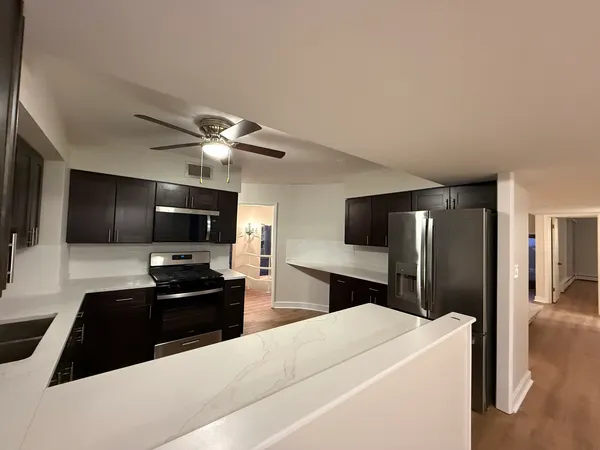 a living room with stainless steel appliances kitchen island granite countertop a refrigerator a stove a microwave oven a sink with island and chairs