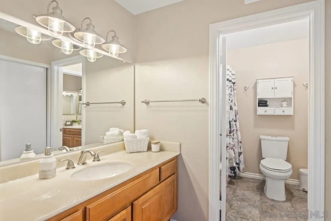 13755 Royal Melbourne Square San Diego, CA 92128 - Photo 52 of 75 a bathroom with a granite countertop sink a toilet and a mirror