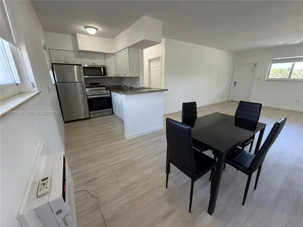 a kitchen with a table chairs refrigerator and microwave