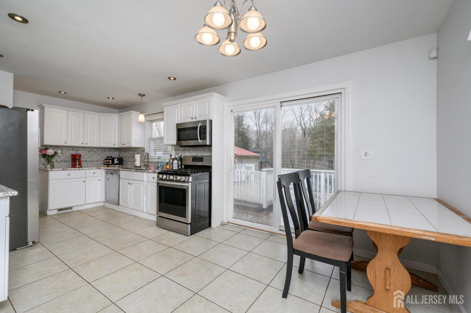 384 Cook Road Jackson, NJ 08527 - Photo 6 of 31 a kitchen with granite countertop a stove a sink dishwasher a dining table and chairs with wooden floor
