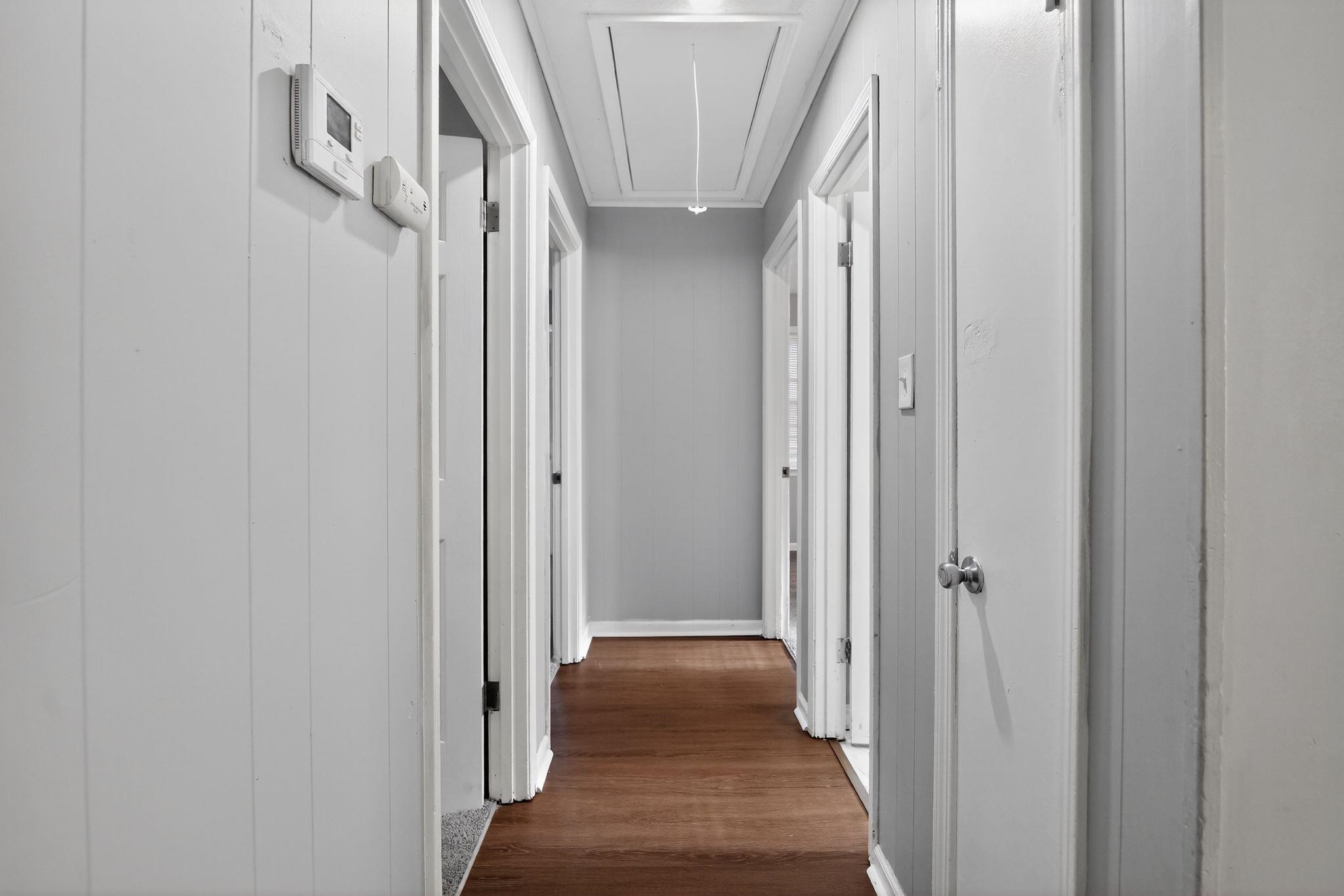 4686 Gill Road Memphis, TN 38109 - Photo 29 of 32 Hallway with wood-finish flooring, white paneling, and multiple doorways