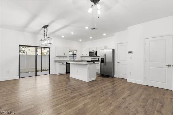 a view of kitchen with stainless steel appliances refrigerator stove and wooden floor