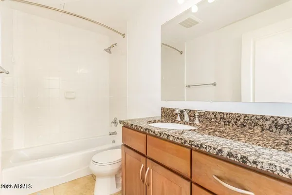 a bathroom with a granite countertop sink a toilet and shower
