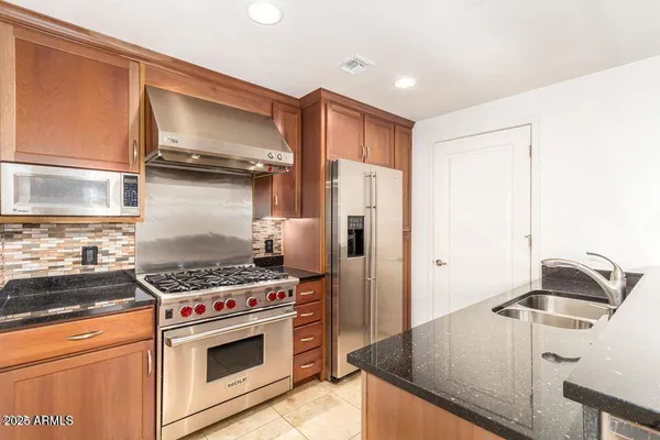 a kitchen with stainless steel appliances granite countertop a sink stove and refrigerator