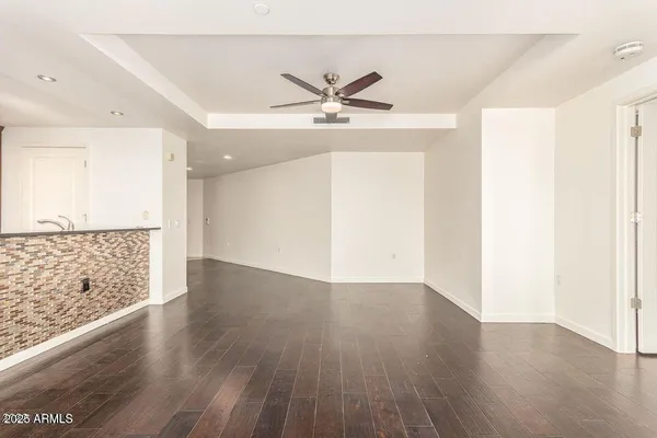 an empty room with wooden floor fan and windows