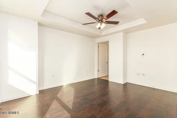 a view of a big room with wooden floor and chandelier fan