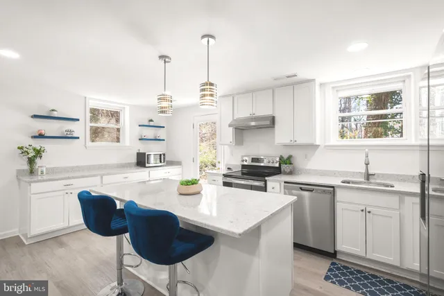 a kitchen with stainless steel appliances granite countertop a sink a stove a refrigerator cabinets and chairs