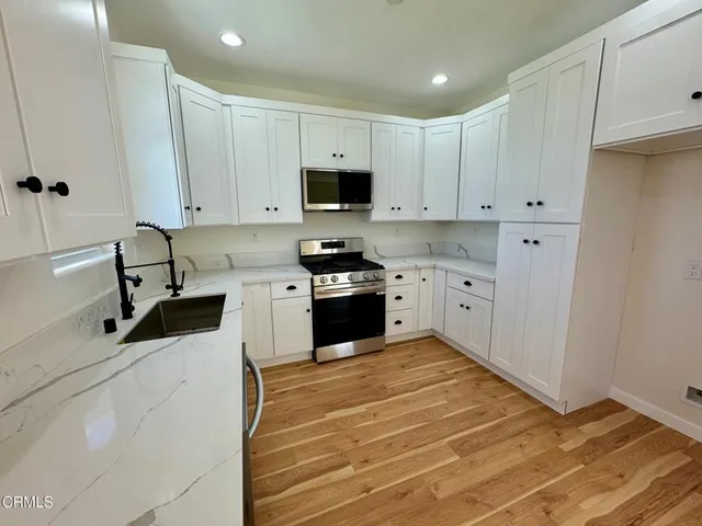 a kitchen with stainless steel appliances granite countertop a stove a microwave and a white cabinets