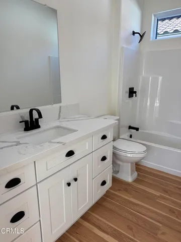 a view of an empty room with wooden floor and a bathroom