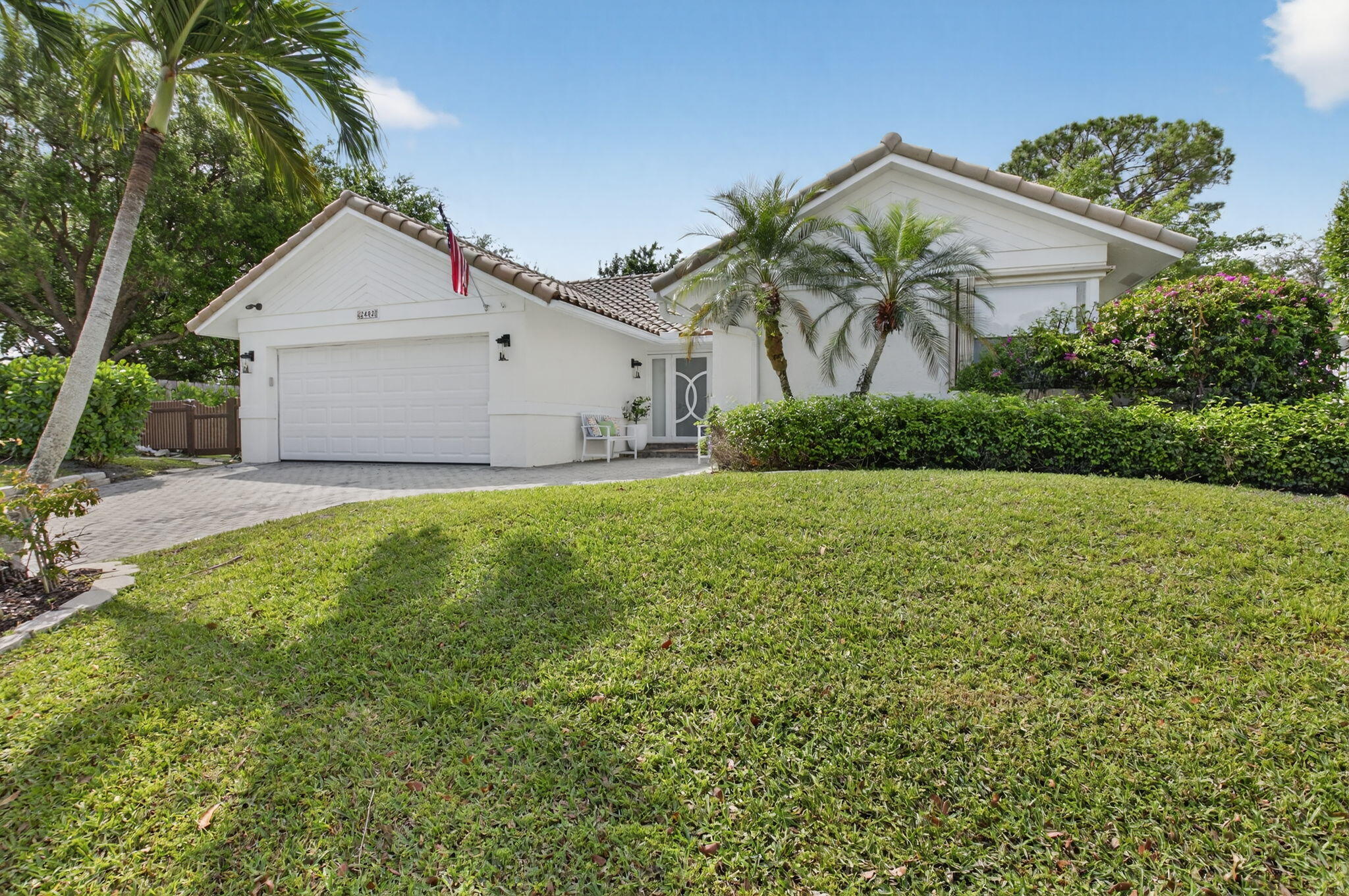 2402 Northwest 30th Street Boca Raton, FL 33431 - Photo 30 of 45 a view of a white house next to a yard with palm trees