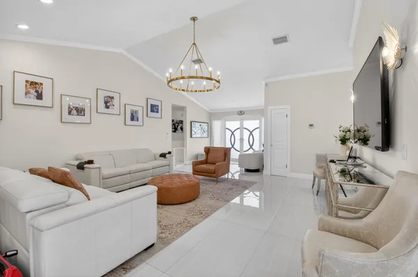 a living room with furniture kitchen view and a chandelier