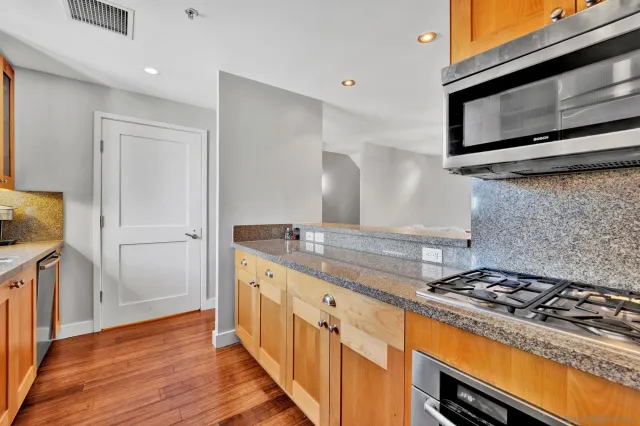 a kitchen with granite countertop a stove and a wooden floor