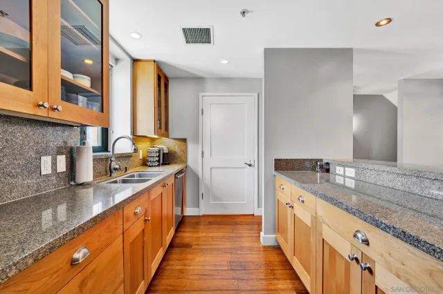 a large kitchen with granite countertop a sink and a wooden floor