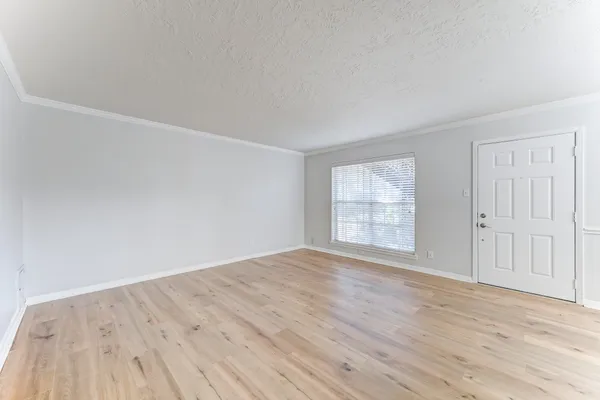 a view of an empty room with wooden floor and window