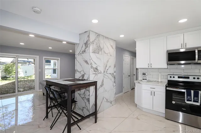 a kitchen with stainless steel appliances kitchen island granite countertop a stove a sink a refrigerator and a microwave