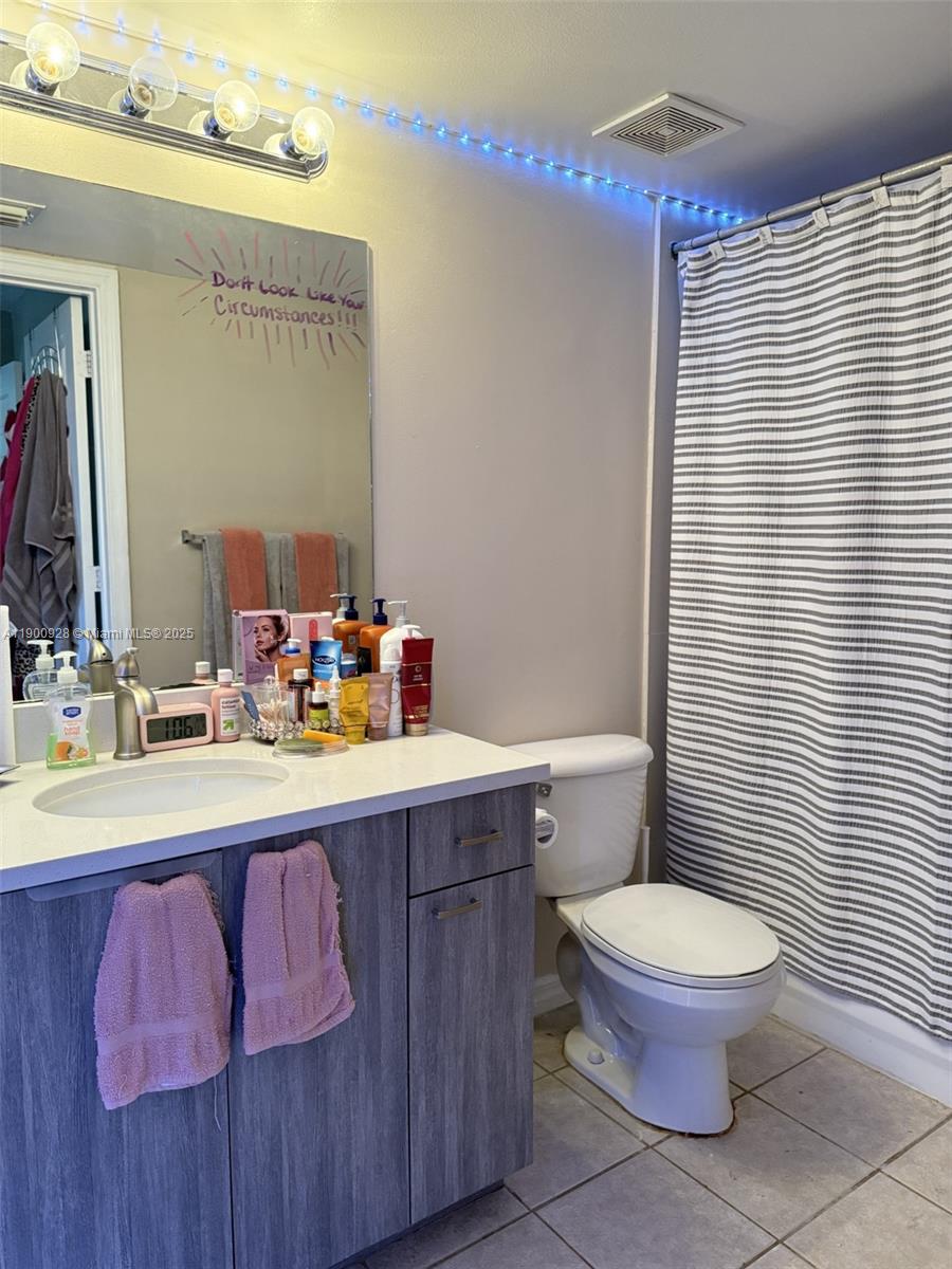 5015 Wiles Road, Unit 207 Coconut Creek, FL 33073 - Photo 11 of 11 a bathroom with a sink a toilet a mirror and shower curtain