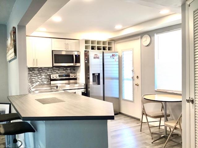 1101 Northeast 191st Street, Unit H301 Miami, FL 33179 - Photo 3 of 18 a kitchen with stainless steel appliances kitchen island granite countertop a sink refrigerator and microwave