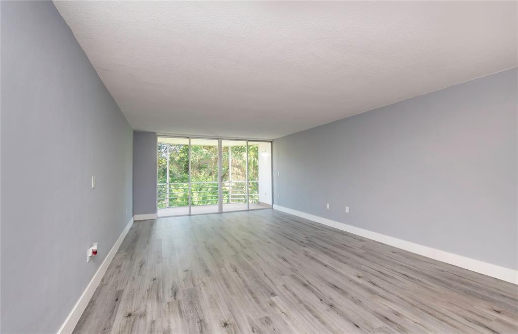 1101 Northeast 191st Street, Unit H301 Miami, FL 33179 - Photo 5 of 18 a view of an empty room with wooden floor and a window