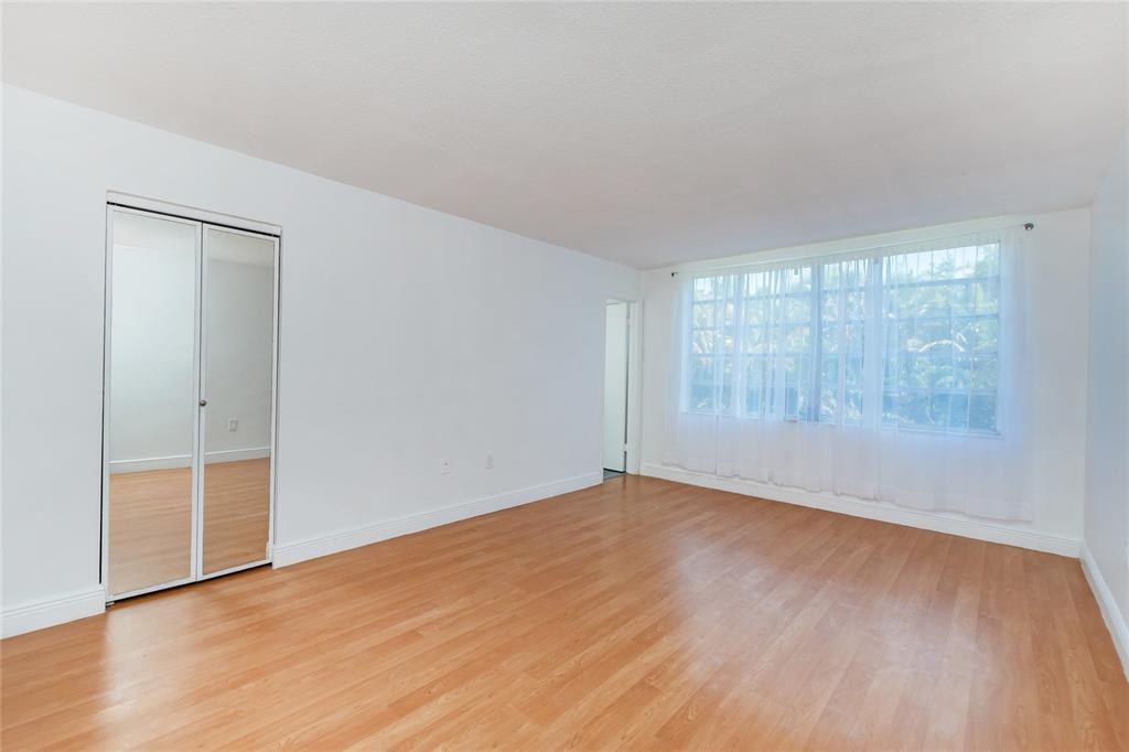 1101 Northeast 191st Street, Unit H301 Miami, FL 33179 - Photo 9 of 18 an empty room with wooden floor and windows