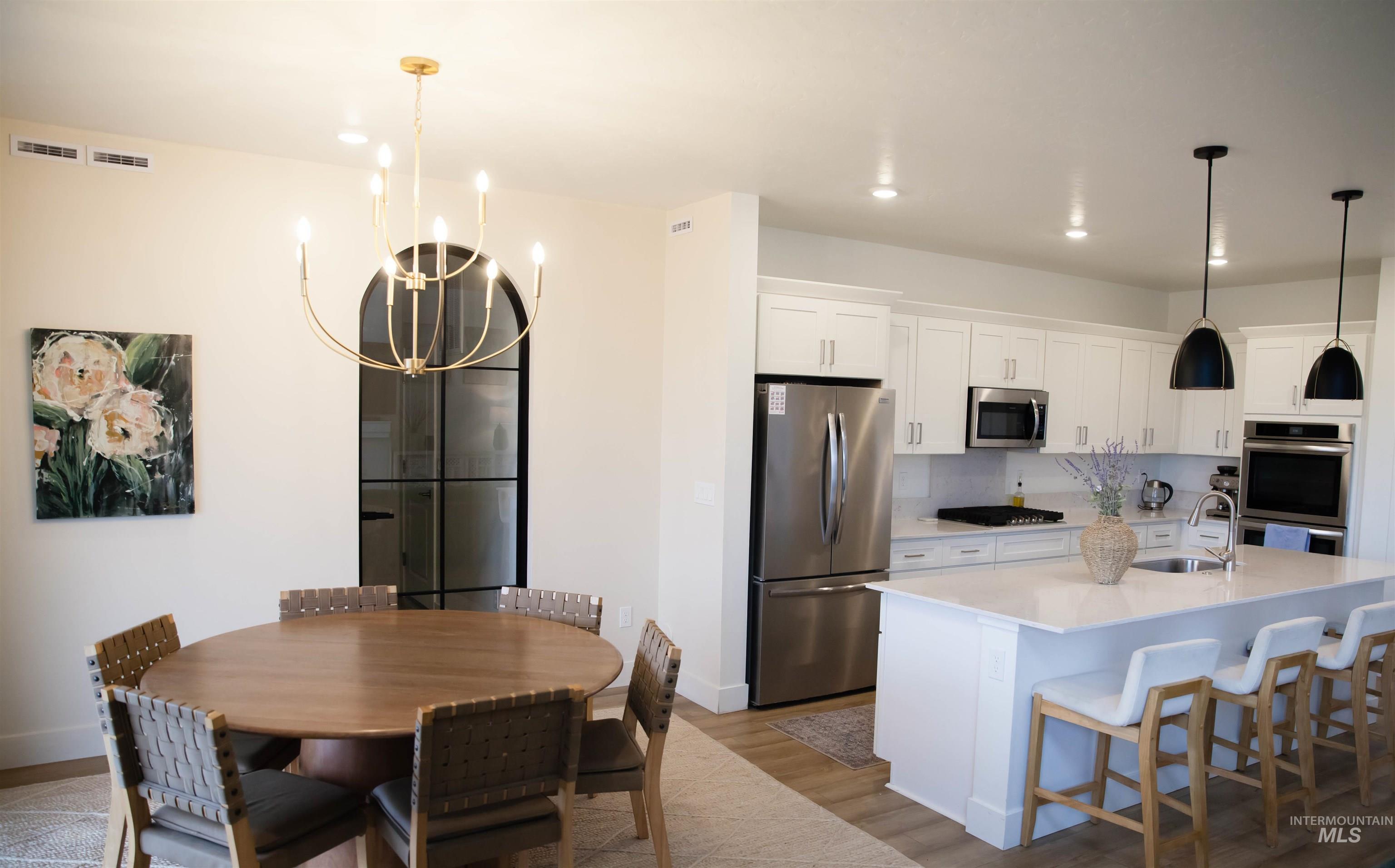 151 Insight Court Middleton, ID 83644 - Photo 10 of 35 Kitchen with light wood-type flooring, stainless steel appliances, white cabinets, a kitchen bar, and tasteful backsplash
