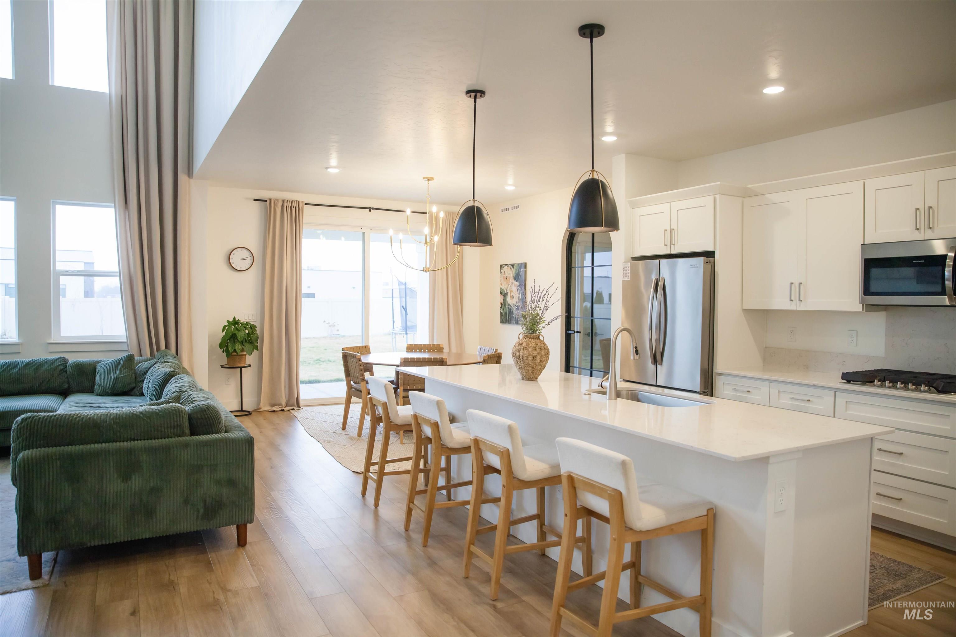 151 Insight Court Middleton, ID 83644 - Photo 2 of 35 Kitchen featuring white cabinets, a kitchen bar, a kitchen island with sink, light wood finished floors, and stainless steel appliances