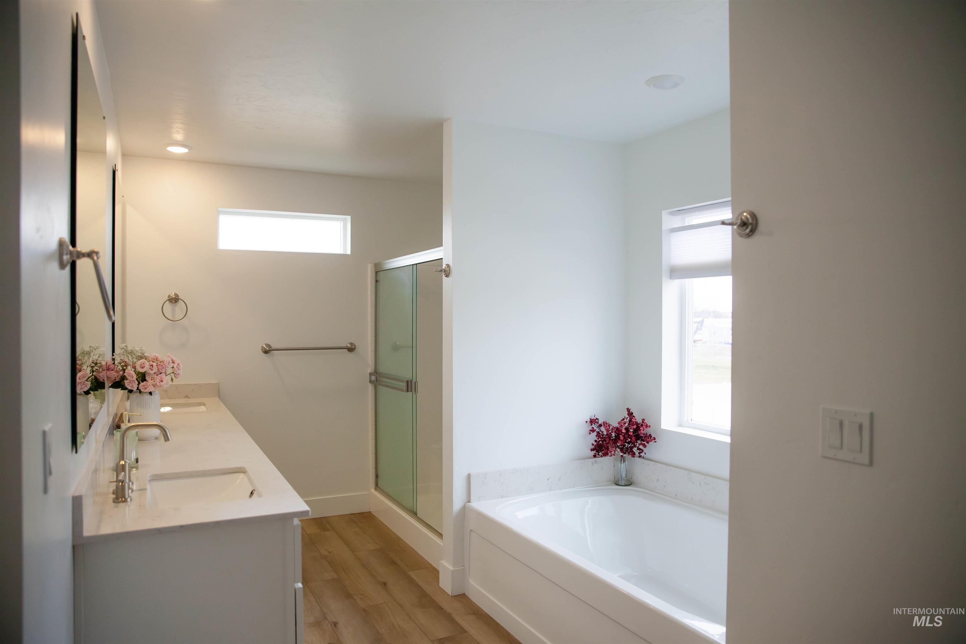 151 Insight Court Middleton, ID 83644 - Photo 20 of 35 Bathroom with double vanity, a garden tub, light wood-type flooring, and a shower stall
