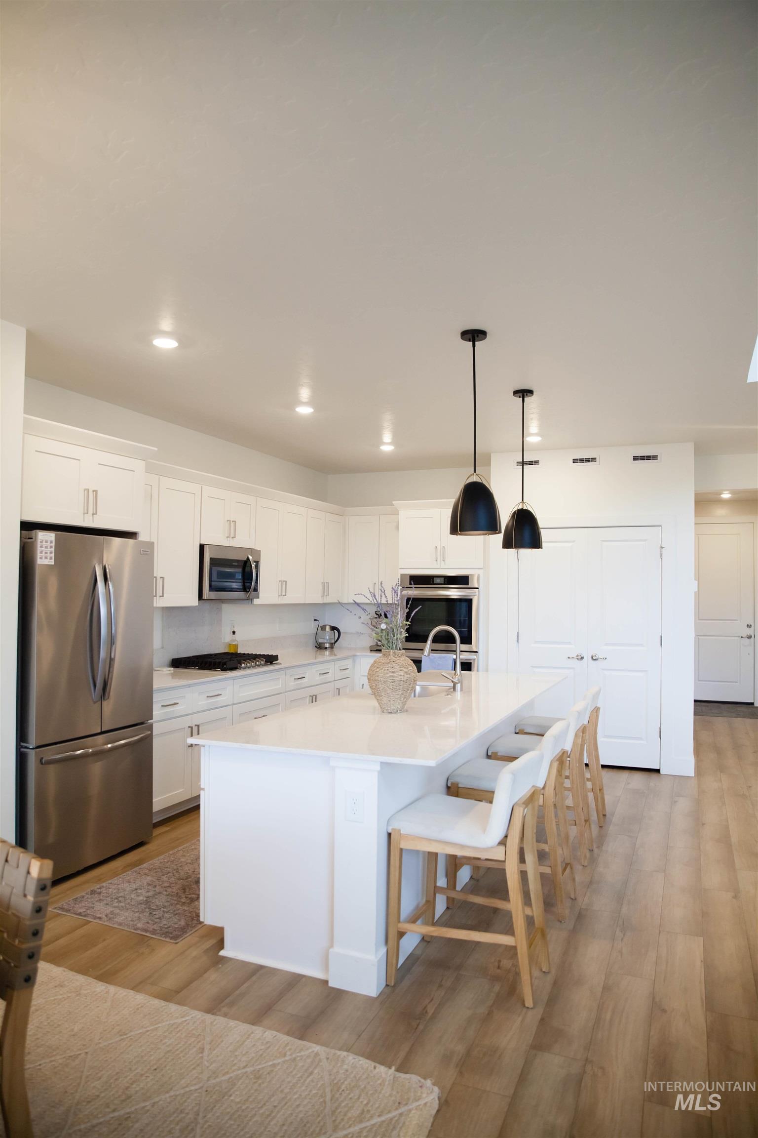 151 Insight Court Middleton, ID 83644 - Photo 4 of 35 Kitchen with light wood-style flooring, stainless steel appliances, white cabinetry, and an island with sink