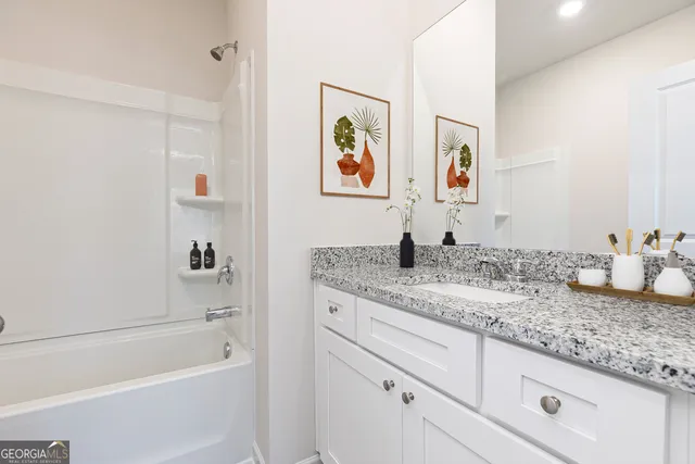 a bathroom with a granite countertop tub sink and mirror