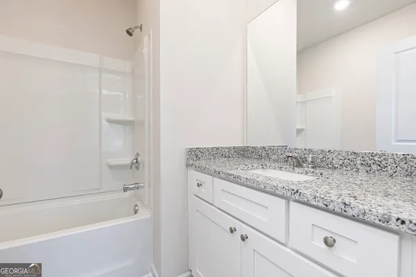 a bathroom with a granite countertop sink and white tub