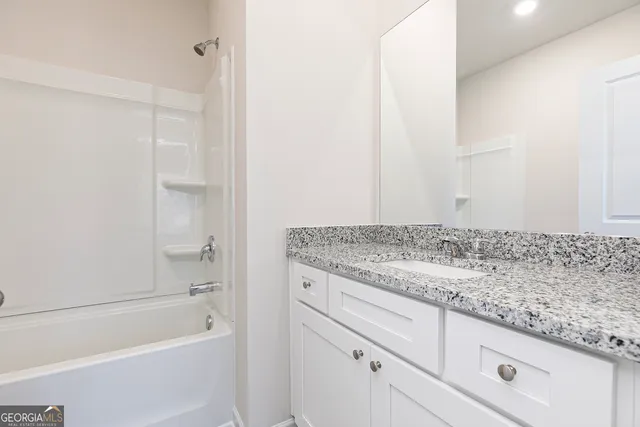 a bathroom with a granite countertop sink and white tub