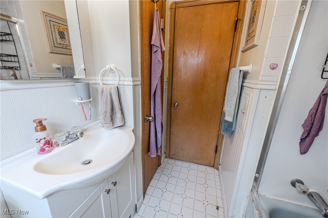 6445 Stanbury Road Cleveland, OH 44129 - Photo 10 of 17 Bathroom featuring wainscoting, vanity, a decorative wall, and enclosed tub / shower combo