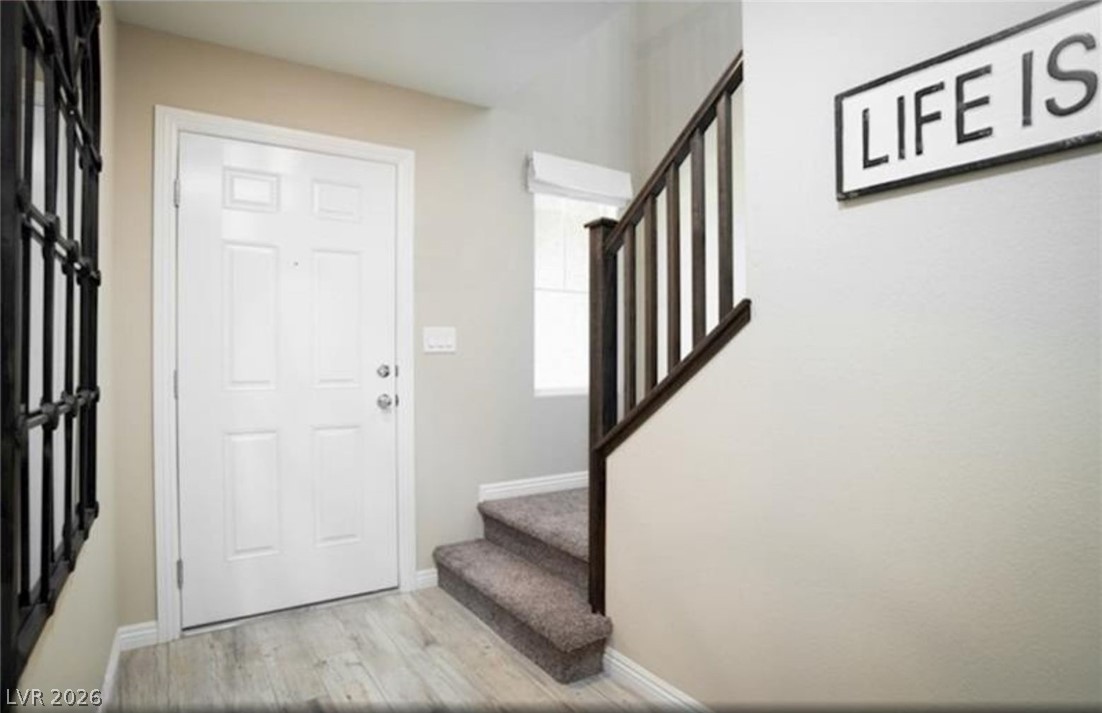 473 Filaree Place Henderson, NV 89015 - Photo 2 of 5 A well-lit entry hall with light wood flooring flows seamlessly into a carpeted staircase with dark wood railings.