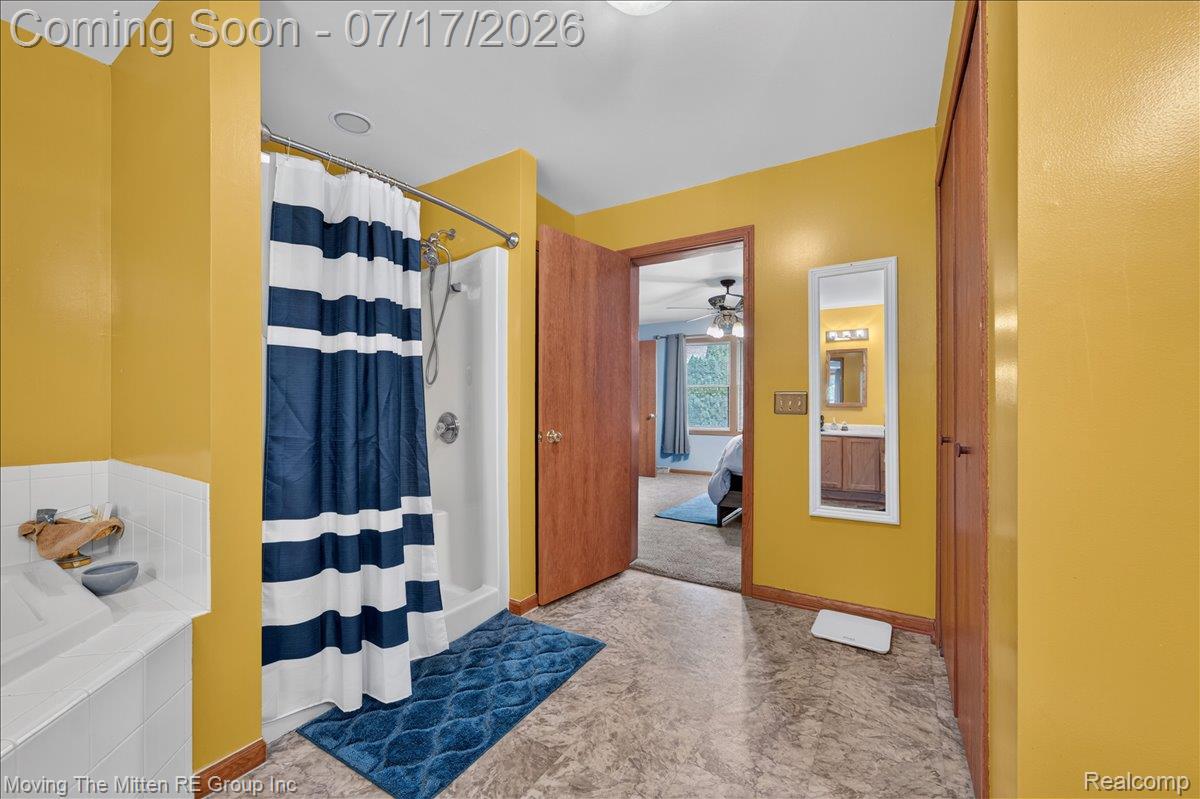40162 Alden Road Belleville, MI 48111 - Photo 20 of 67 Bathroom featuring a white shower stall with a chrome fixture, a white tiled bathtub, wood-finish doors, and a full-length wall mirror