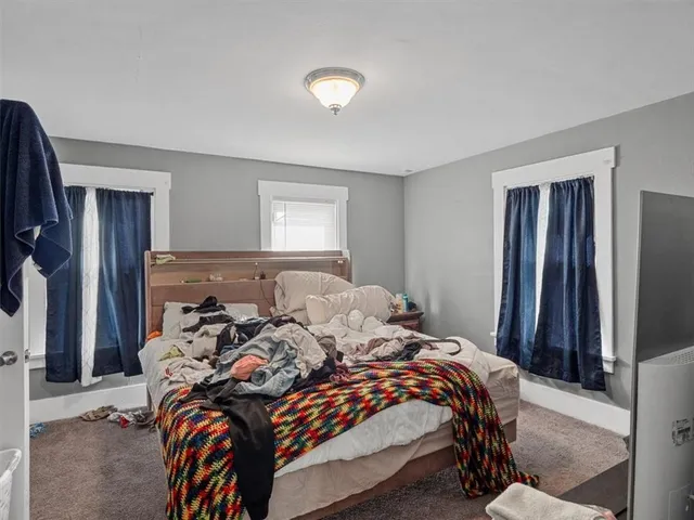 a bed sitting in a bedroom and chair next to a window
