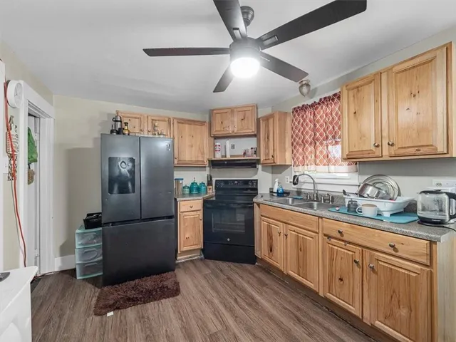 a kitchen with stainless steel appliances granite countertop a refrigerator a sink dishwasher a stove and white cabinets with wooden floor